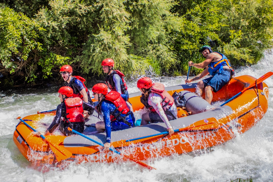 Group in a guided raft laughing on the Rogue River after going through a big wave.