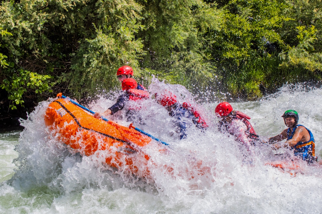 Raft half-way through big wave in Nugget Falls on the Rogue River with guide laughing.