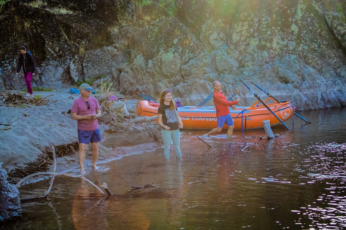 Rafters skipping rocks on the Rogue River from a beach near a raft