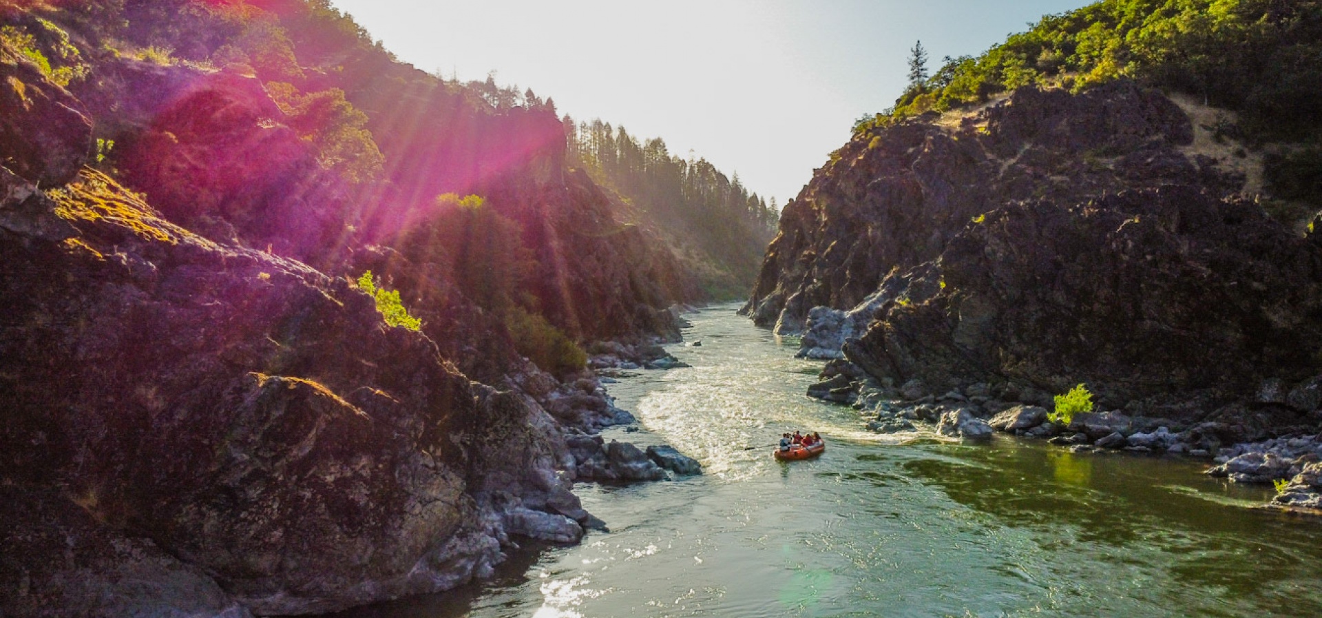 Raft floating into Hellgate canyon on the Rogue River at sunset